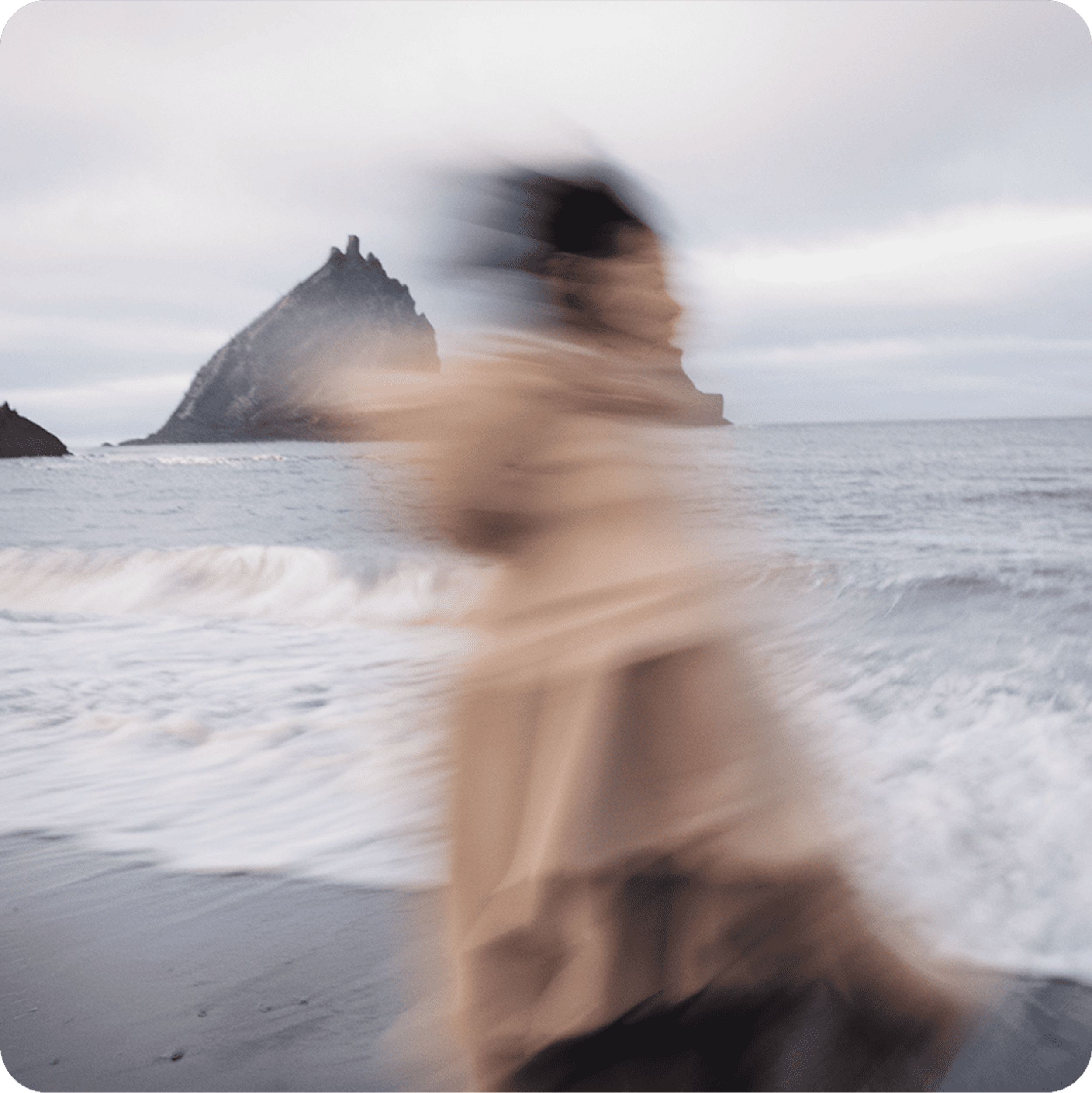 Blurred image of a person on a beach against a cloudy sky