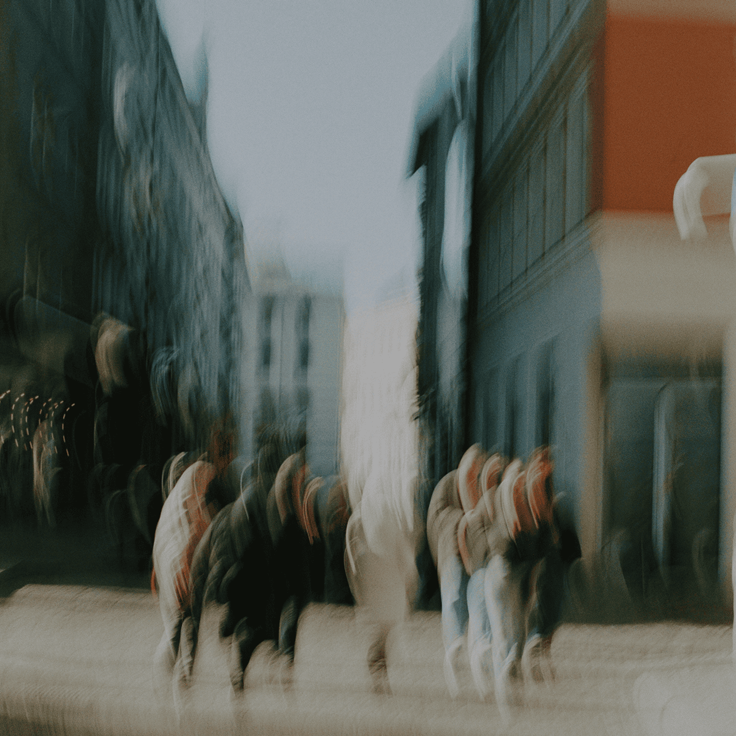 Motion-blurred people walking through a city street