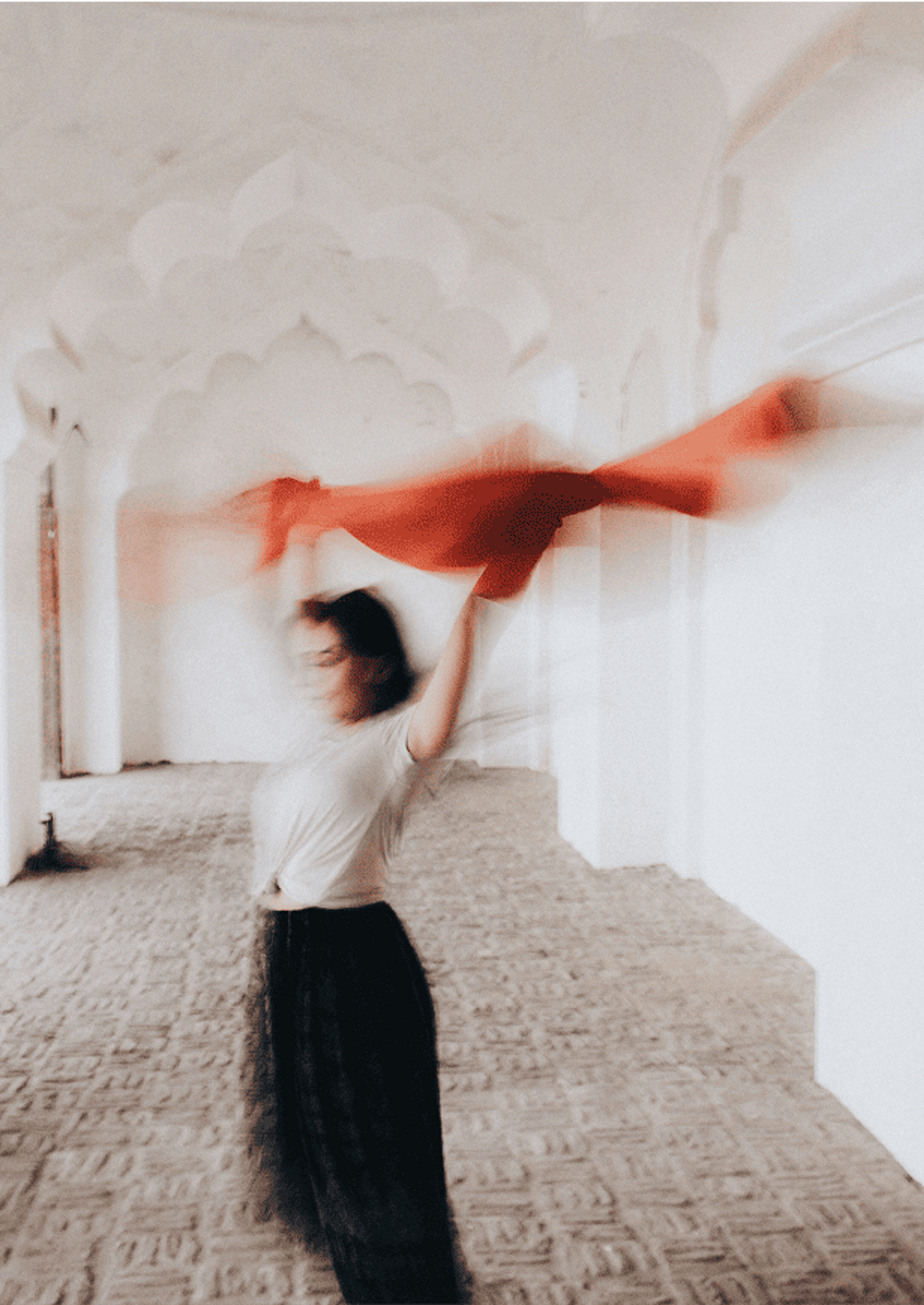 Blurry image of a woman dancing indoors while holding a red scarf