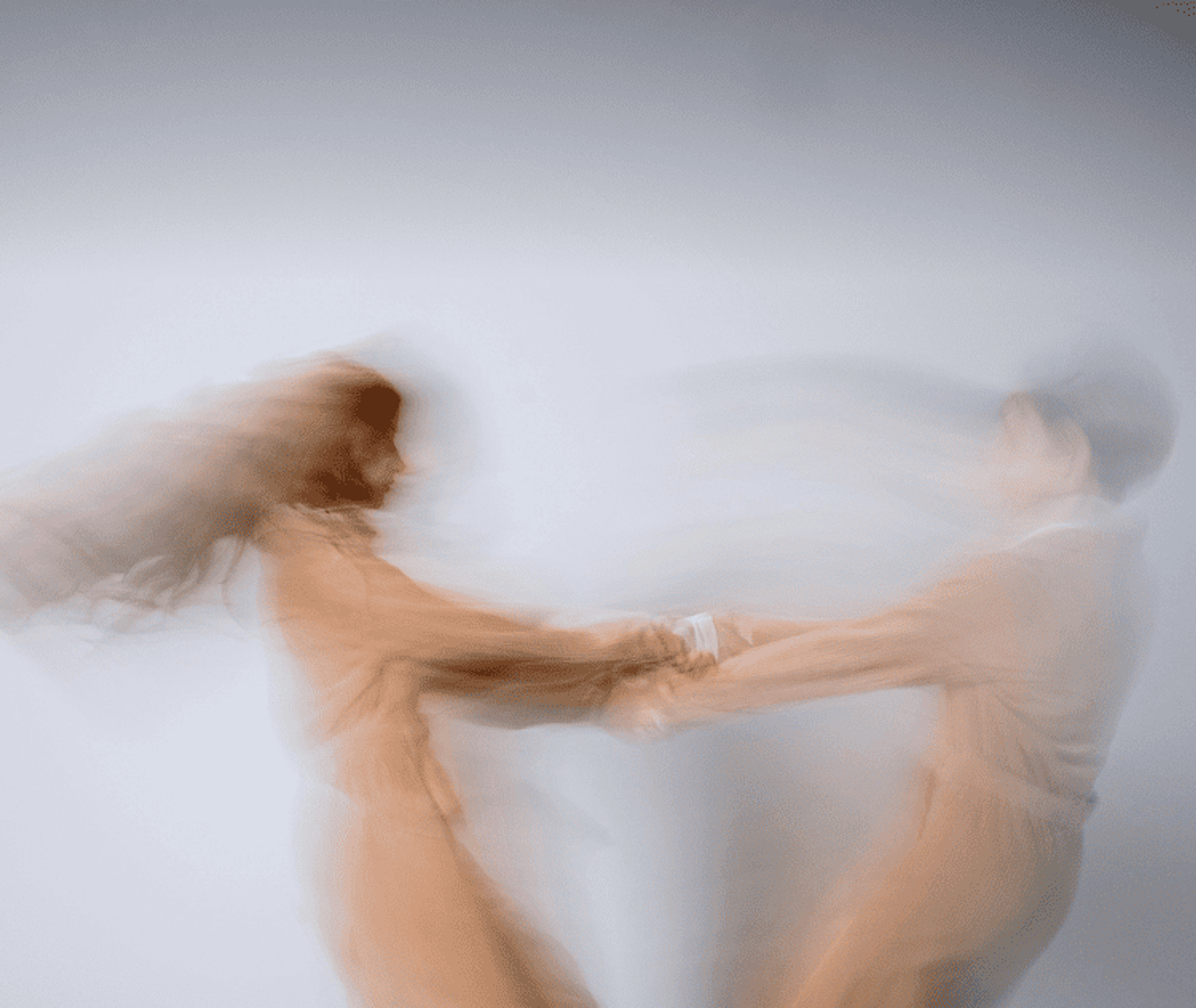 Motion-blurred image of two people spinning while holding hands