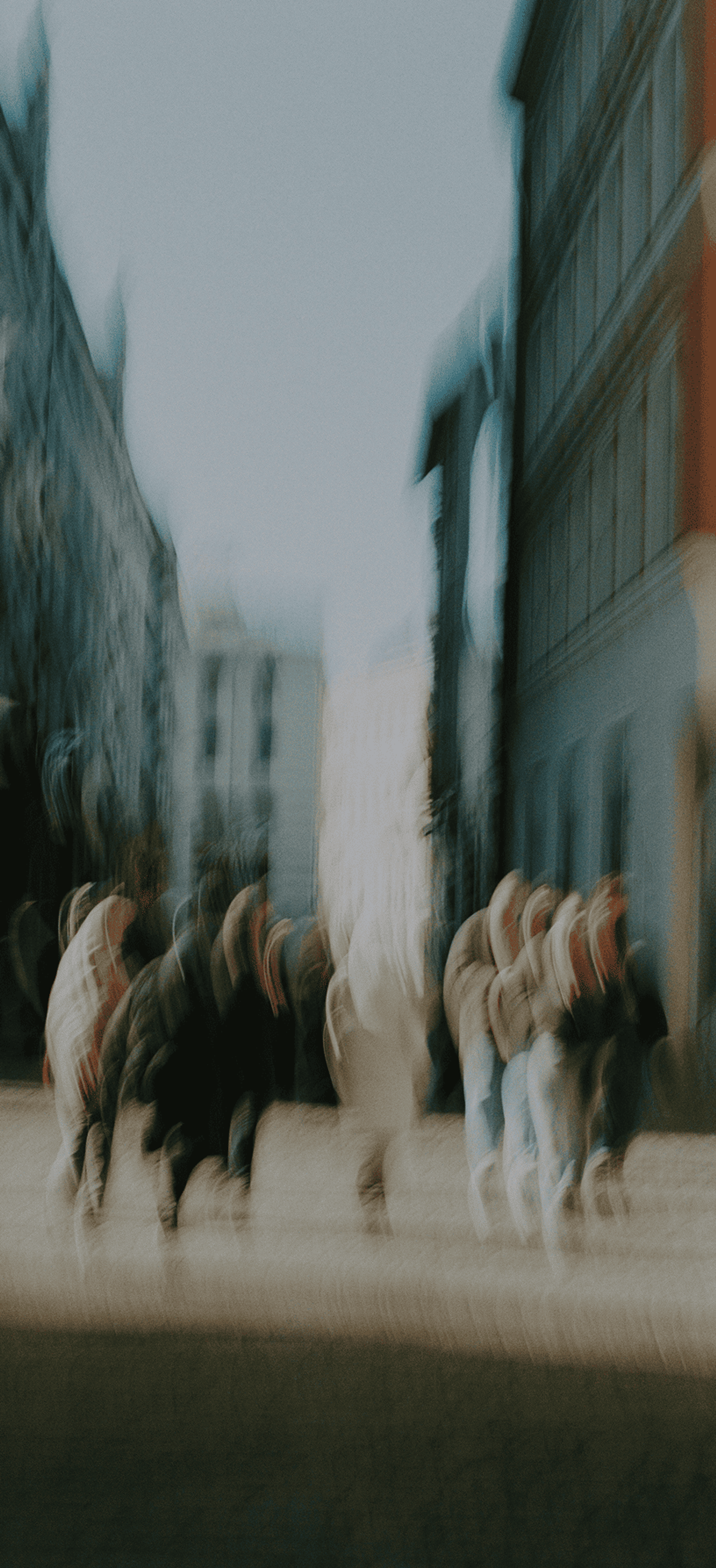 Motion-blurred people walking through a city street