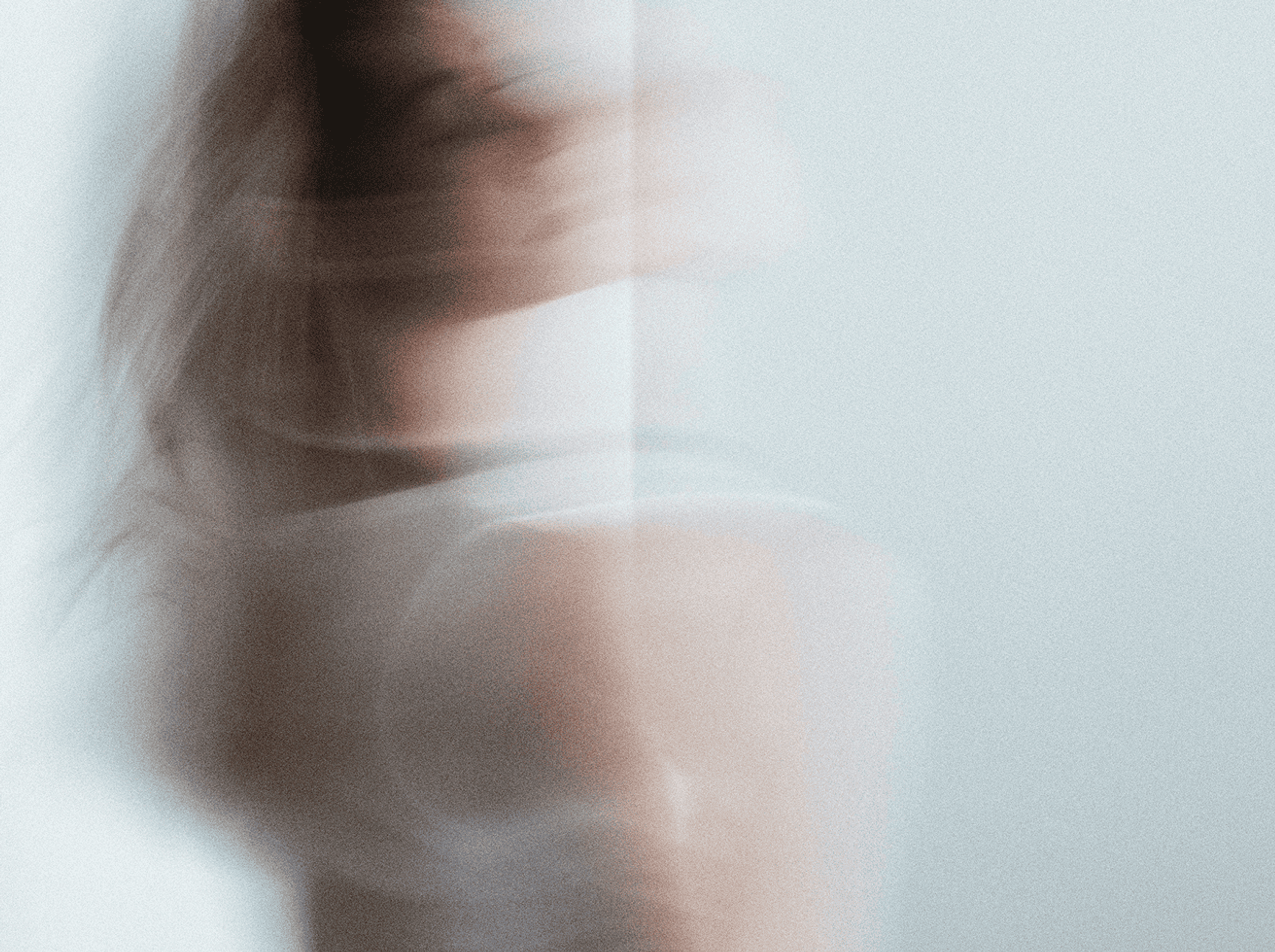 Blurry image of a woman standing agains a light background