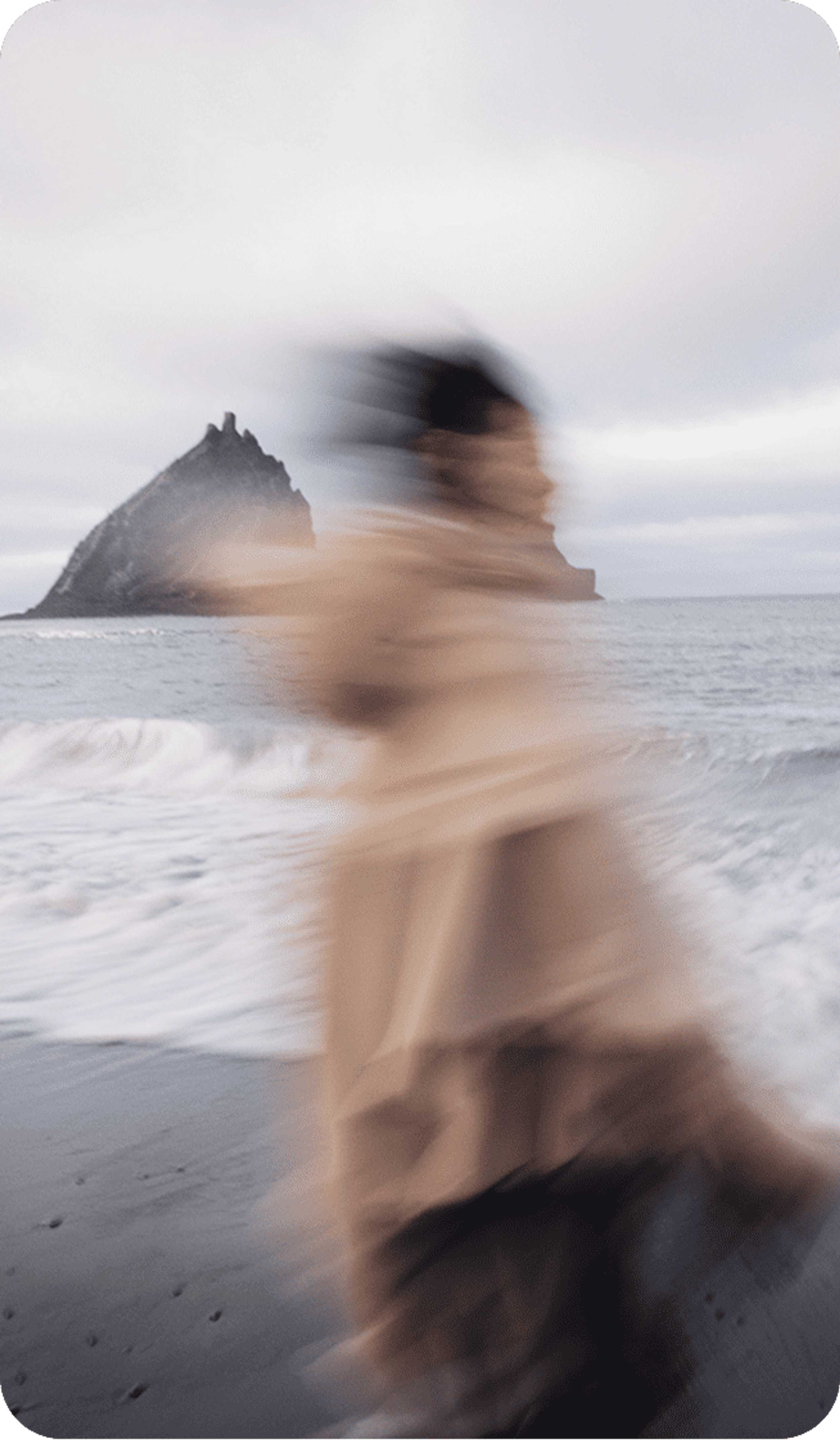 Blurred image of a person on a beach against a cloudy sky