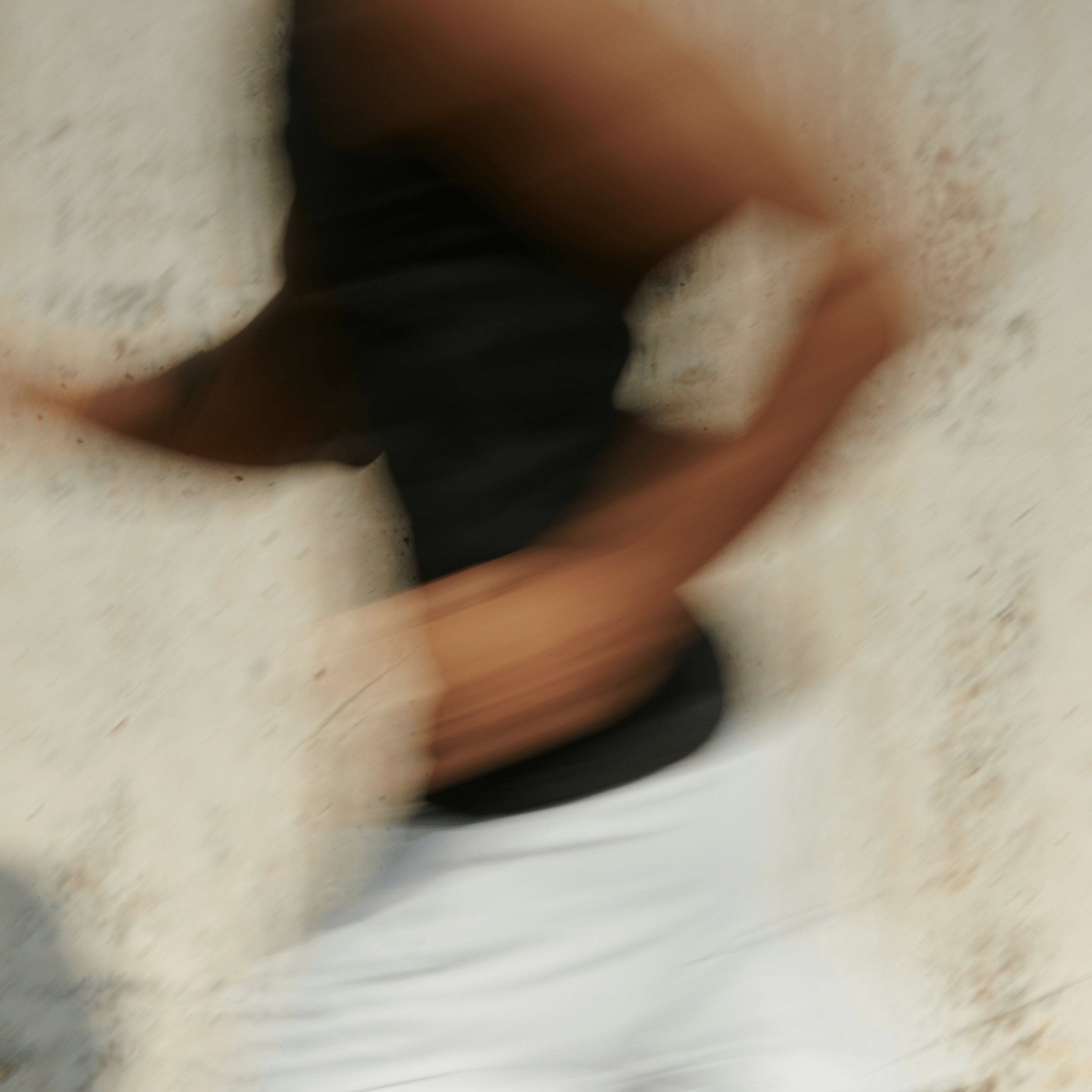 Blurry motion shot of a person running past a light-colored wall