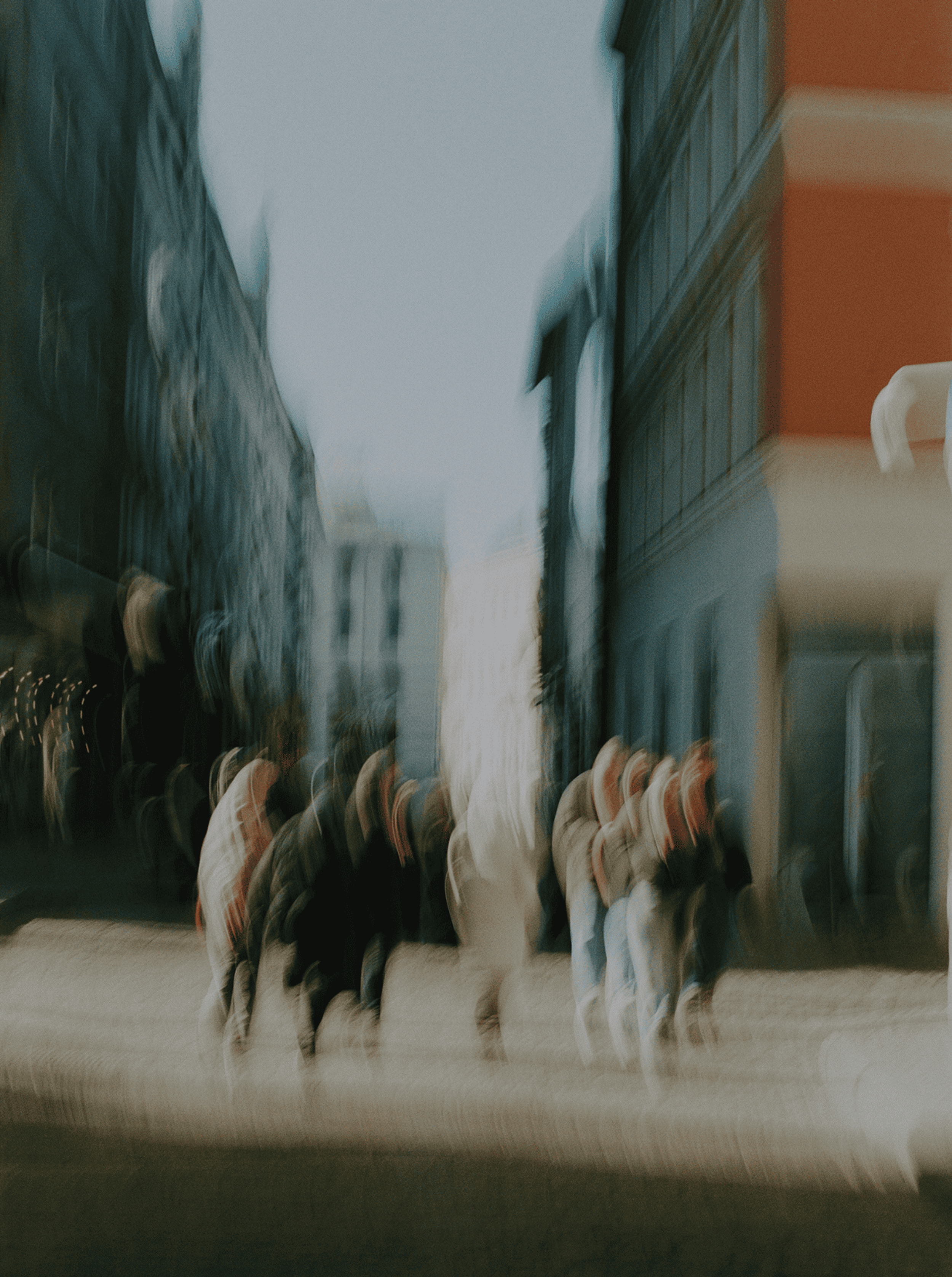 Motion-blurred people walking through a city street