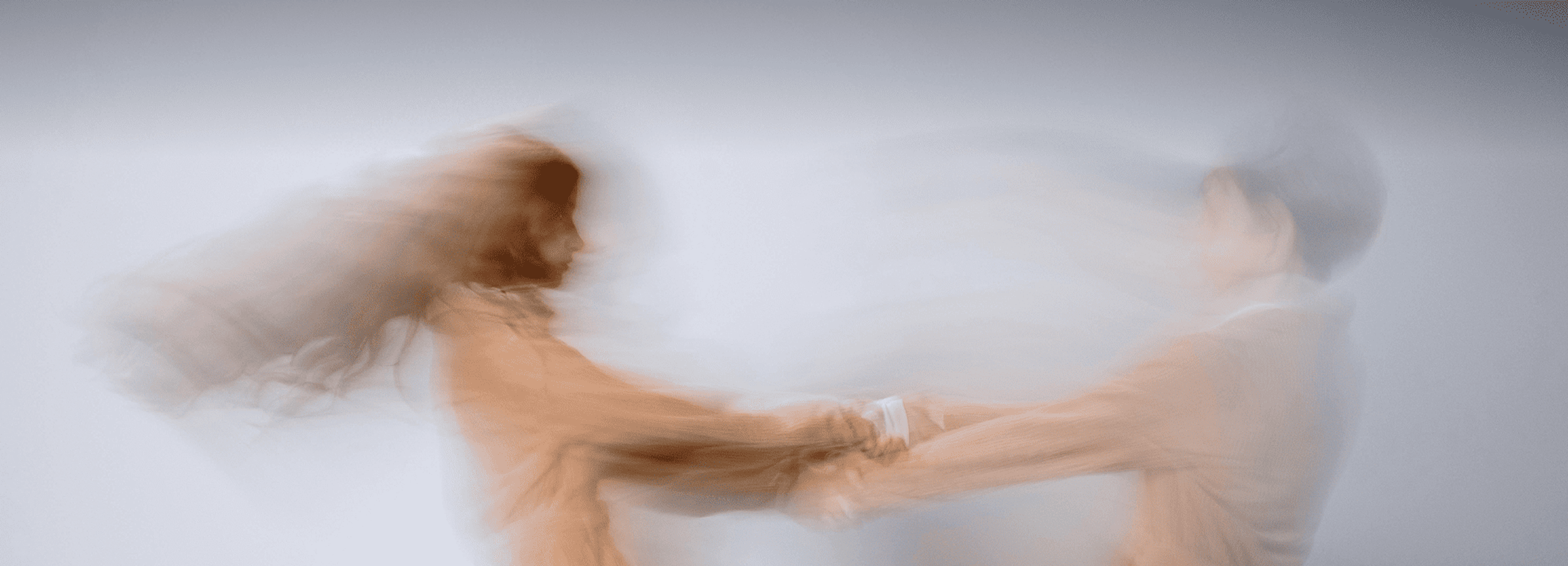 Motion-blurred image of two people spinning while holding hands