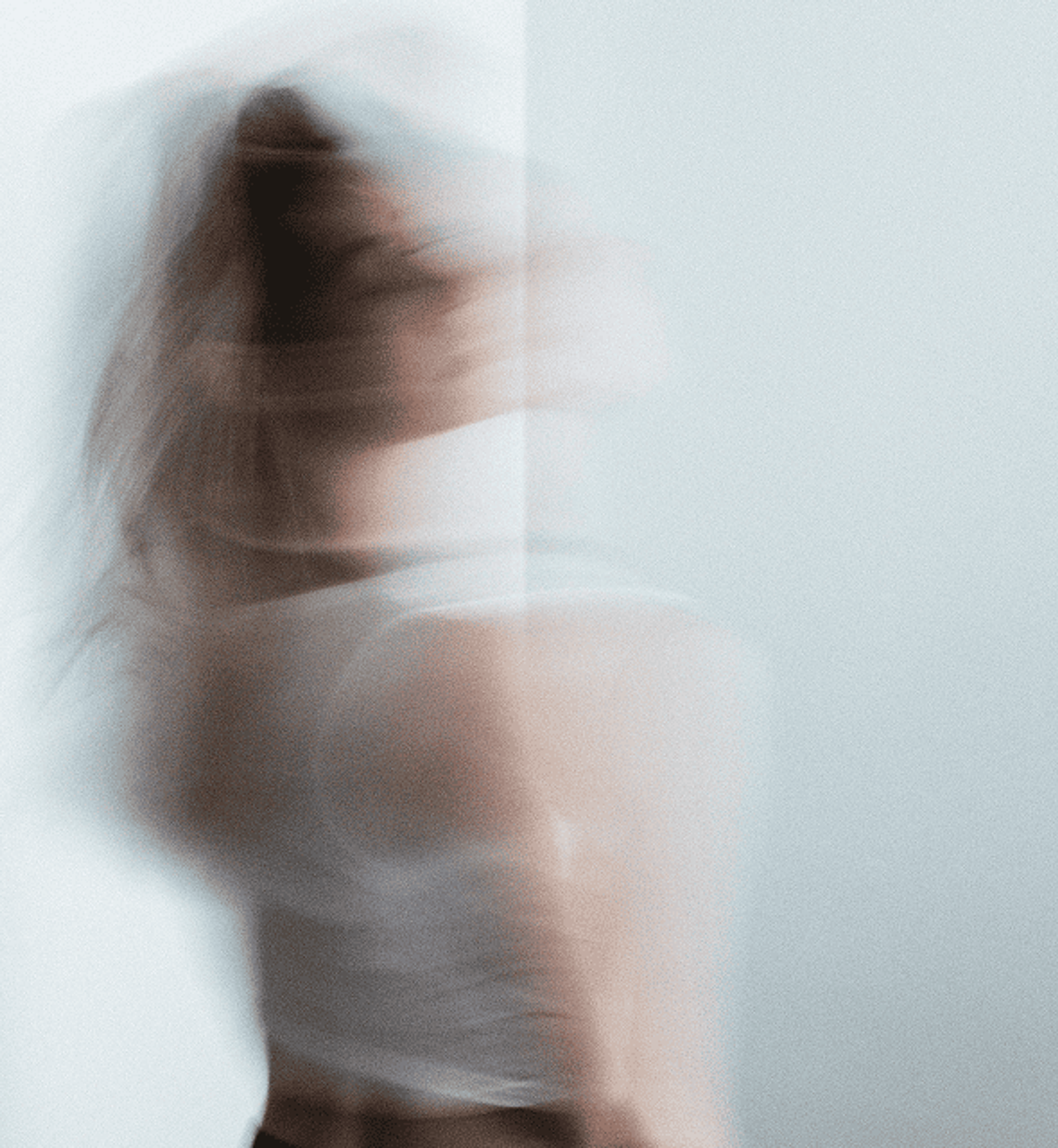 Blurry image of a woman standing agains a light background